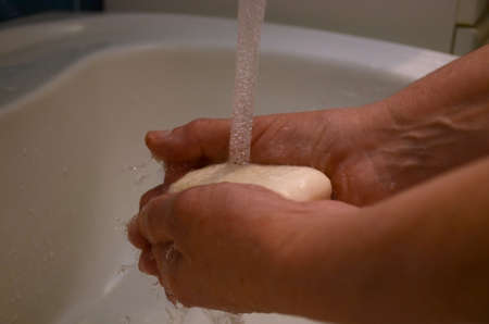 A woman washes her hands with soap under a tap with water. Prevention and control of the outbreak of...