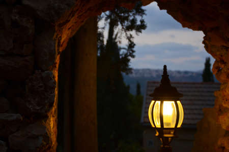 Glowing lantern at night on the cave window. Evening sky and house roof. Twilight in the Middle East.の写真素材