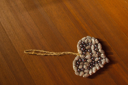 Handmade heart made of cones and beads on a table, flat lay and copy space
