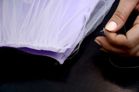Seamstress collects lilac fabric closeup. Excess threads are removed. Small business concept.