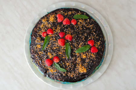 Fresh chocolate cake with strawberries and mint on platter. Horizontal photo of home baking, flat layの写真素材