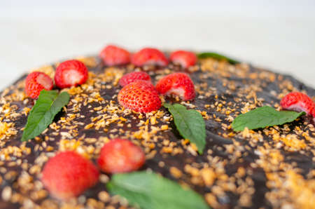 Fresh chocolate cake with strawberries and mint on platter. Photo of homemade baked goods with selective focusの写真素材