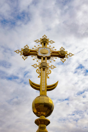 Cross on a background of the sky with gray clouds. Golden orthodox cross close-up. Religion concept,...