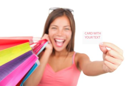 Shopping woman showing sign / business card. Very excited asian-caucasian model over seamless white. Shallow depth of field with focus on the blank sign / card. の写真素材