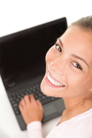 Studying young woman writing / working on her laptop. Beautiful asian caucasian mixed race.の写真素材
