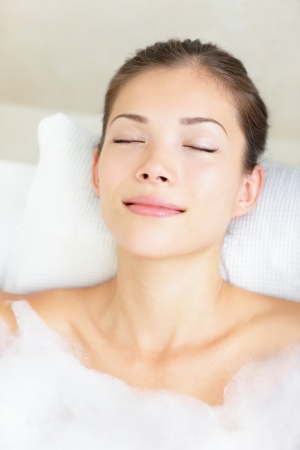 Woman in bath relaxing. Closeup of young asian woman in bathtub bathing with closed eyes.の写真素材