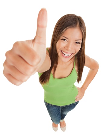 Fun high angle portrait of an attractive vivacious young woman giving a big thumbs up of success and approval isolated on white