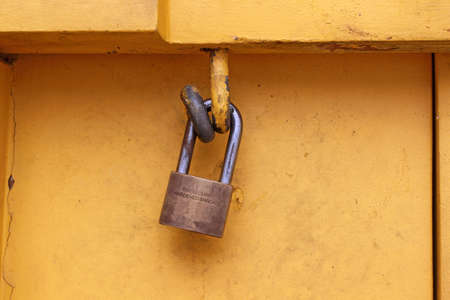 The yellow door with old padlock and old safety hasp.の写真素材