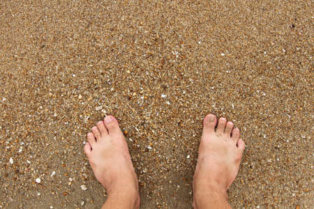 Feet on the sand on the beach.