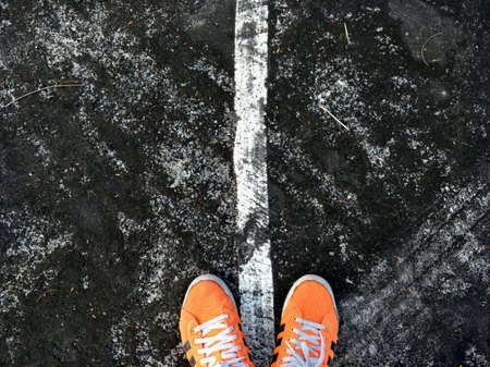 Orange shoes on old roads marked on wet asphalt.の写真素材