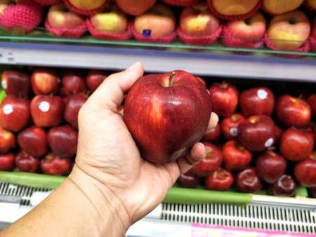 Man hand choosing red apple in the supermarket.