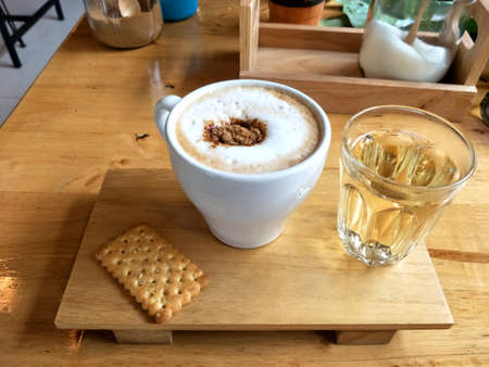 Hot cappuccino coffee in a white glass on wooden floor.の写真素材