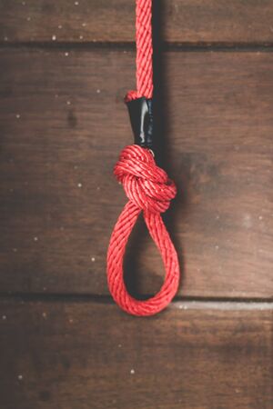 Red Rope knot on old wooden board background.