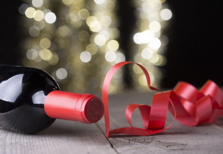 heart shape ribbon and bottle of red winein front of gold glitter backgroundの写真素材