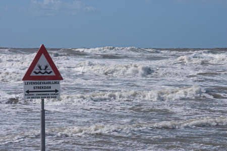 A sign warns for the risk of drowning by dangerous currents cause by a dam in the sea