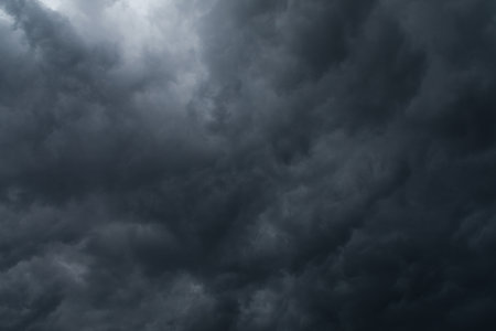 A dark sky filled with clouds and a small bright spot.