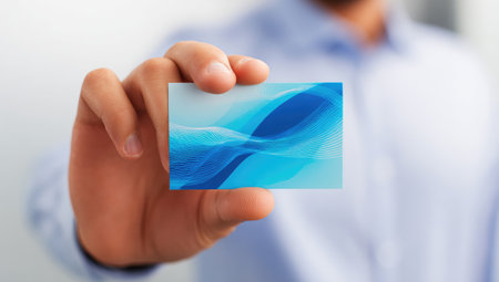 Close-up of hand holding business card with abstract designの素材