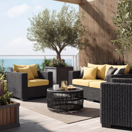 A patio scene displays a modern outdoor furniture set with black woven frames and yellow cushions. A round coffee table sits in front of the seating area. An olive tree in a large planter, along with other greenery, enhances the space, lit by bright daylight. This setting could be used for lifestyle, home decor, and leisure themes.の素材