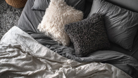 An overhead shot showcases a bed adorned with pillows and bedding. The color palette primarily features shades of gray and white, creating a tranquil aesthetic. The textures include soft, fluffy pillows and smooth sheets. Suitable for diverse applications, including home decor and lifestyle concepts, the image has potential commercial and editorial usage.の素材