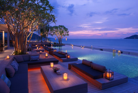 An outdoor lounge area features comfortable seating, ambient lighting, and a serene ocean backdrop. Warm tones and soft lights illuminate the scene, creating a relaxing atmosphere. The image could be suitable for lifestyle, travel, or hospitality related projects, illustrating leisure and comfort.の素材