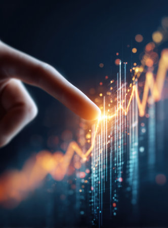 A close-up view depicts a finger interacting with a glowing financial graph against a dark background. The image features a shallow depth of field, with bright highlights and bokeh effects. This visual could be used to represent concepts related to business, investments, and economic growth. Suitable for various editorial and commercial applications.の素材
