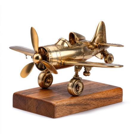 A detailed model airplane, crafted from gold-colored metal, is displayed on a wooden base. The object features a propeller and wings, showcasing intricate design. The piece is set against a white background, highlighting its form and color. Suitable for commercial or editorial applications related to aviation or collectibles.の素材
