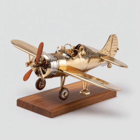 A detailed model airplane, crafted from shiny gold material, is displayed on a small wooden base. The design exhibits vintage qualities with its propeller and cockpit details. The image features clean lighting and a neutral background, making it suitable for various commercial purposes, including product displays and editorial content.の素材