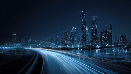A nighttime cityscape presents illuminated skyscrapers against a dark backdrop. Light trails streak across the foreground, suggesting movement. The scene is dominated by cool blues and hints of brighter lights. This image could be used for various commercial projects related to urban development or technology.の素材
