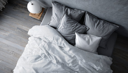An overhead shot showcases a minimalist bedroom featuring a bed with striped bedding and gray pillows. The room displays a neutral color palette with a textured wall and wooden floor. This composition may be suitable for home decor projects, interior design presentations, or lifestyle-related content.の素材