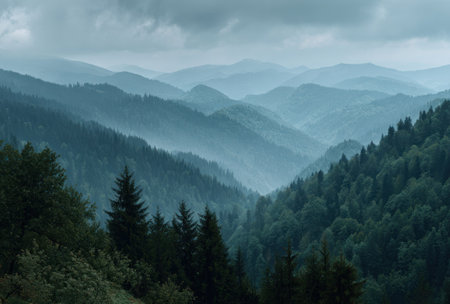A scenic landscape presents a range of mountains, gradually receding into the distance. The image features a misty, atmospheric effect, with shades of blue and green dominating the color palette. This type of image could be used for various projects, including editorial features, website design, and print materials.の素材