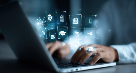 A person is shown using a laptop, interacting with a series of digital icons hovering above the keyboard. The image displays a cool blue and white color palette, with soft lighting enhancing the futuristic elements. This image is suitable for illustrating concepts of technology, connectivity, or online business applications.の素材