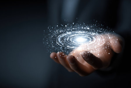 A hand cradles a digitally rendered galaxy with swirling patterns and radiating energy, illuminated by bright lights. The image features a dark background, highlighting the glowing object held within. This visual concept suggests themes of technology, innovation, and connection. Suitable for various commercial and editorial applications.の素材