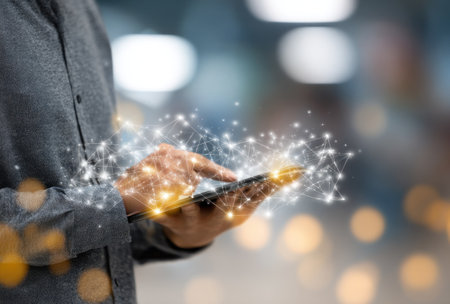 A person uses a smartphone, interacting with a representation of a digital network. The image presents a shallow depth of field, soft lighting, and blurred backgrounds. White and gold particles emanate from the phone, creating a futuristic visual aesthetic. This could be used for technology, communication, and digital concepts.の素材