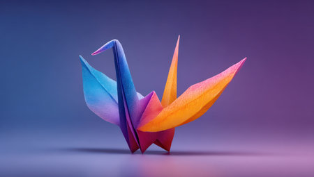 A vibrant origami crane is the main subject against a smooth gradient background. The paper art features a spectrum of colors, including blue, purple, and orange. The image utilizes soft lighting, creating a polished, almost ethereal appearance. This image is suitable for various commercial purposes, particularly for illustrations and design projects.の素材