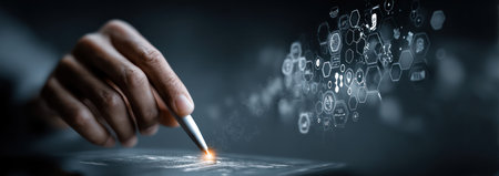 A hand holds a stylus above an interactive surface, with a futuristic illustration of data points in the background. The image presents a dark, dynamic composition with a shallow depth of field, emphasizing the glowing pen tip. It may be suitable for illustrating concepts of technology, data, or innovation.の素材