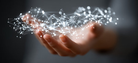 A close-up view displays a hand cradling a complex network of interconnected nodes and lines. The image presents a futuristic concept with bright, glowing elements set against a blurred background. This visual could be utilized for presentations or various commercial and editorial designs related to technology and networking.の素材