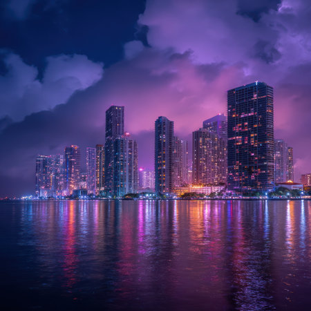 A nighttime cityscape showcases towering buildings along a waterfront. The scene is illuminated by artificial lights reflecting on the water's surface, enhanced by a dramatic sky with dark clouds and shades of purple. This imagery is suitable for various uses, including editorial and commercial projects.の素材