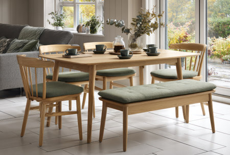 A dining area showcases a wooden table accompanied by chairs and a bench with green cushions. The scene is illuminated by natural light, suggesting a bright and airy atmosphere. Suitable for illustrating home decor, furniture arrangements, or lifestyle concepts, this image presents a clean and inviting space with potential uses in editorial and commercial contexts.の素材
