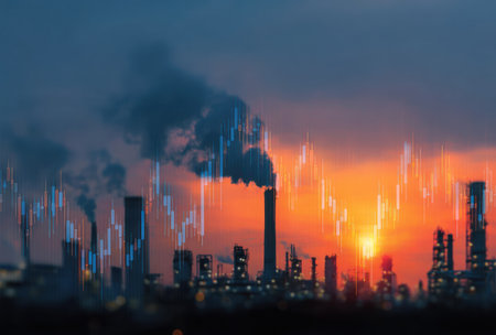 An industrial complex is silhouetted against a vibrant sunset sky, featuring smokestacks emitting plumes. The composition employs a low-angle perspective with blurred foreground elements. The image integrates a digital overlay of financial market data, suggesting themes related to industry and economy. Suitable for conceptual illustrations.の素材