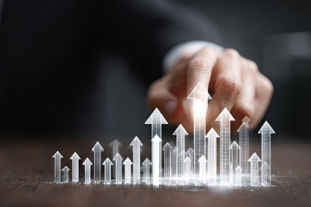 A hand indicates rising arrows, symbolizing growth and success in a business context. The image displays a shallow depth of field, with soft lighting and a blurred background. This visual could be used in presentations, marketing materials, or financial reports to illustrate progress and development.の素材