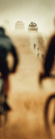 This image depicts cyclists on a road with vehicles in the distance, evoking a sense of travel. The composition features blurred foreground elements with a focus on depth. Warm tones and hazy lighting characterize the scene, which could be suitable for editorial or commercial purposes related to transportation or outdoor activities.の素材