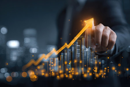 A hand touches a glowing arrow chart superimposed over a cityscape, illustrating business growth. The image uses a dark color palette with orange and blue highlights. The composition suggests financial success and progress. Suitable for various business and economic related publications and marketing materials.の素材