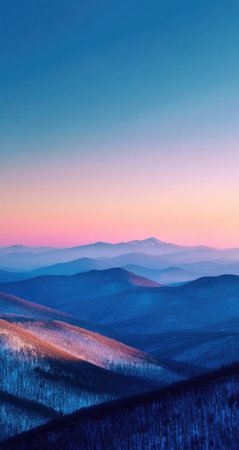 An expansive mountain vista unfolds under a gradient sky blending soft pinks and blues. The landscape features layered mountain ridges in varying shades of blue, with hints of snow. The image showcases natural light, ideal for various editorial and commercial applications.の素材