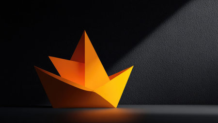 An orange paper boat rests against a dark backdrop, illuminated by a single light source. The composition highlights geometric shapes and contrasting shadows, creating a dynamic visual effect. The image may be suitable for illustrating concepts of travel, journey, or creativity in commercial and editorial contexts.の素材