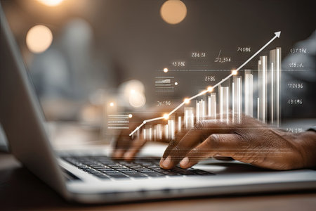 An individual uses a laptop with a digital chart indicating financial growth. The image shows hands typing on a keyboard, with graphical data superimposed. The composition employs shallow depth of field, with soft lighting and a neutral background. Suitable for illustrating business, finance, or technology concepts.の素材