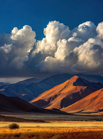 The image features a mountainous landscape with a prominent cloud formation against a vibrant blue sky. The composition emphasizes natural beauty, with warm tones on the mountains contrasting with the cool hues above. This visual could be used for various projects needing a scenic backdrop or to convey themes of adventure and exploration.の素材