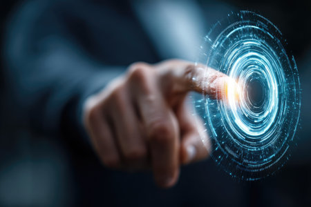 A close-up view displays a person's hand interacting with a glowing digital interface. The circular design features blue and orange hues, with a blurred background. The image suggests a technology-focused context, useful for concepts related to communication and innovation. This style suits various commercial and editorial applications.の素材