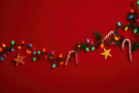 A vibrant overhead view showcases a decorative Christmas garland with colorful illuminated lights and traditional candy canes. The composition features a rich red backdrop, enhancing the festive mood. This image highlights holiday cheer and can be used for promotional campaigns or editorial content related to Christmas celebrations.の素材