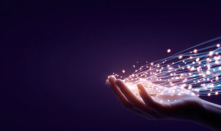 A hand is reaching upward, cradling a stream of glowing particles against a deep purple backdrop. The image features a shallow depth of field, highlighting the hand and the luminous strands. The color palette emphasizes purples and blues with bright highlights. This conceptual image may be suitable for illustrating themes of technology, innovation, or communication.の素材