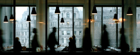 The image features silhouetted figures near windows, with hanging lights creating an atmosphere of mystery. A blurred city view is visible outside. The composition presents a minimalist style with neutral colors and soft lighting, ideal for various editorial and commercial applications.の素材